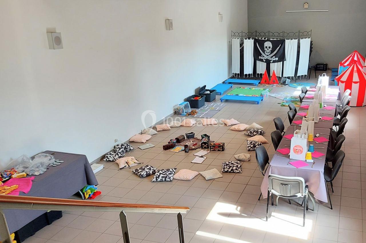 Salle aménagée avec des coussins disposés en cercle, une table décorée pour un repas et un décor sur le thème pirate.