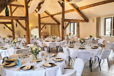 Façade d'un bâtiment en pierre avec une entrée principale, un drapeau publicitaire et une cour pavée.