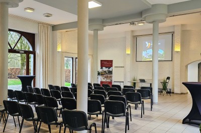 Façade d'un bâtiment en pierre avec une entrée principale, un drapeau publicitaire et une cour pavée.