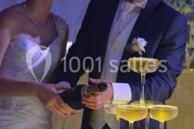 Miniature Location salle Beaudéduit (Oise) - LFK Réceptions #6 Pièce montée en forme d'anneaux entrelacés avec des figurines de mariés, entourée de bouteilles de champagne.