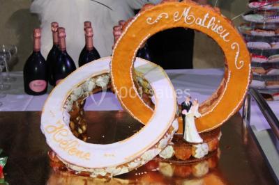 Miniature Location salle Beaudéduit (Oise) - LFK Réceptions #23 Pièce montée en forme d'anneaux entrelacés avec des figurines de mariés, entourée de bouteilles de champagne.