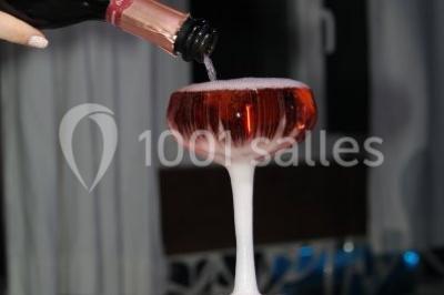 Miniature Location salle Beaudéduit (Oise) - LFK Réceptions #18 Pièce montée en forme d'anneaux entrelacés avec des figurines de mariés, entourée de bouteilles de champagne.