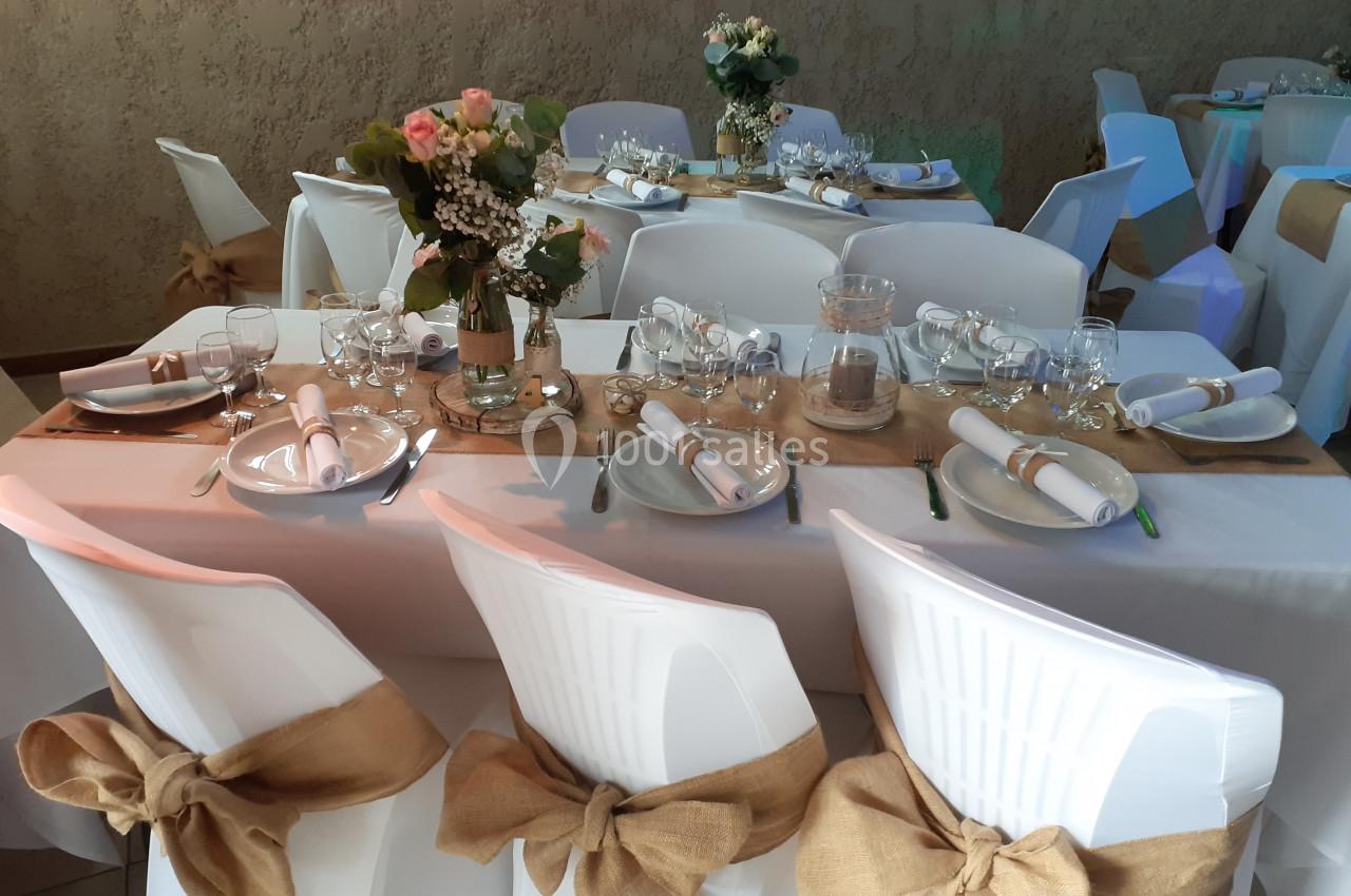 Location salle Beaudéduit (Oise) - LFK Réceptions #11 Table décorée pour un événement avec nappes blanches, chaises ornées de rubans en toile de jute et centre de table floral.