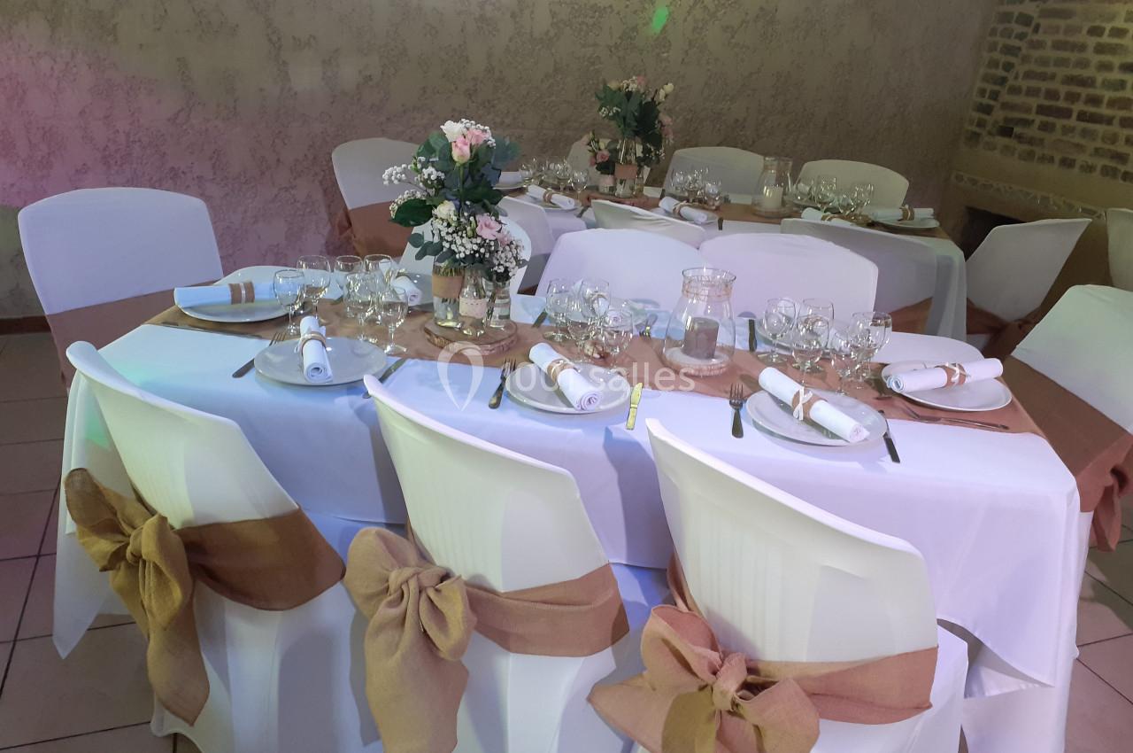 Location salle Beaudéduit (Oise) - LFK Réceptions #13 Salle décorée pour un événement avec tables rondes dressées, nappes blanches, rubans beige et compositions florales.