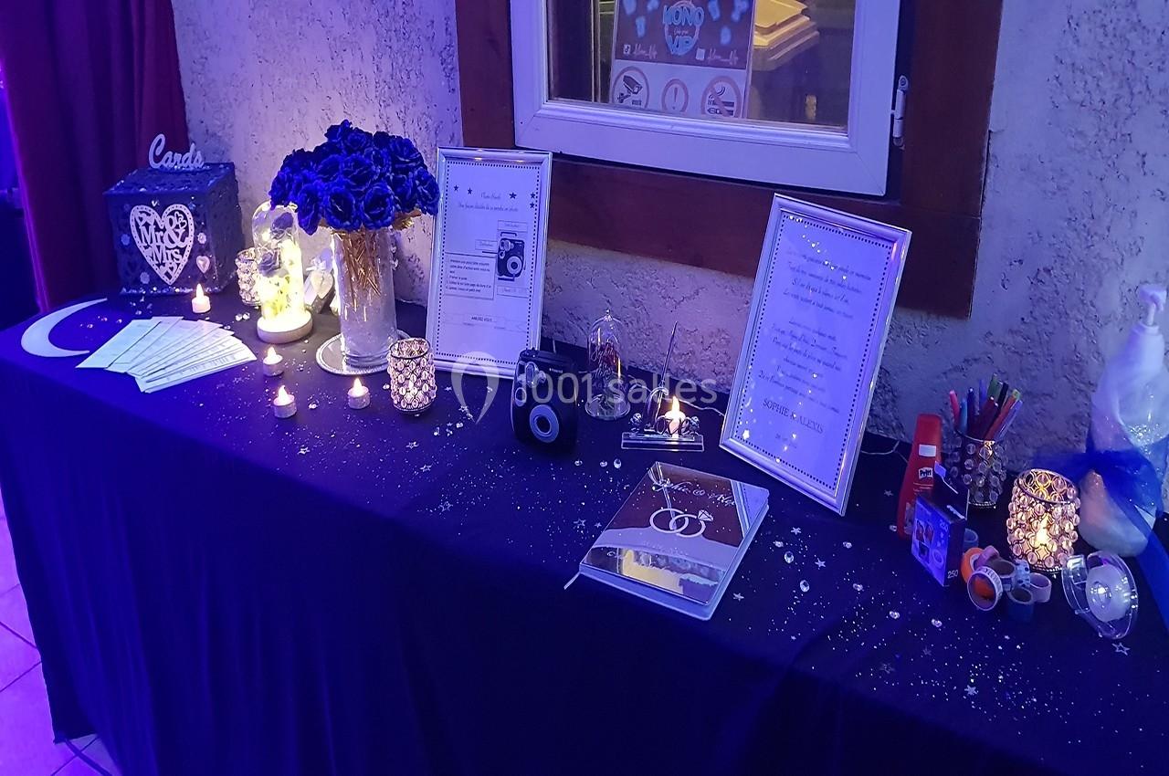 Location salle Beaudéduit (Oise) - LFK Réceptions #7 Table décorée pour un événement avec bougies, fleurs, cadres, accessoires photo et livre d'or sur une nappe sombre.