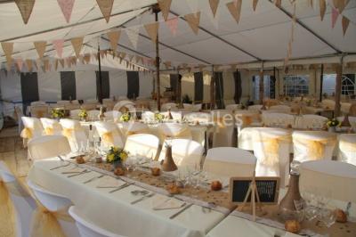 Miniature Agrandissement de la salle Pièce montée en forme d'anneaux entrelacés avec des figurines de mariés, entourée de bouteilles de champagne.