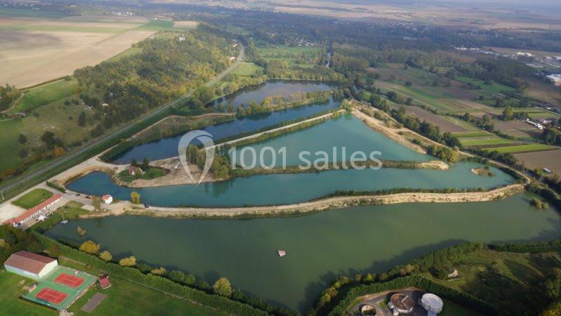 Vue aérienne d'un complexe de plans d'eau entouré de végétation, avec des bâtiments et des champs à proximité.