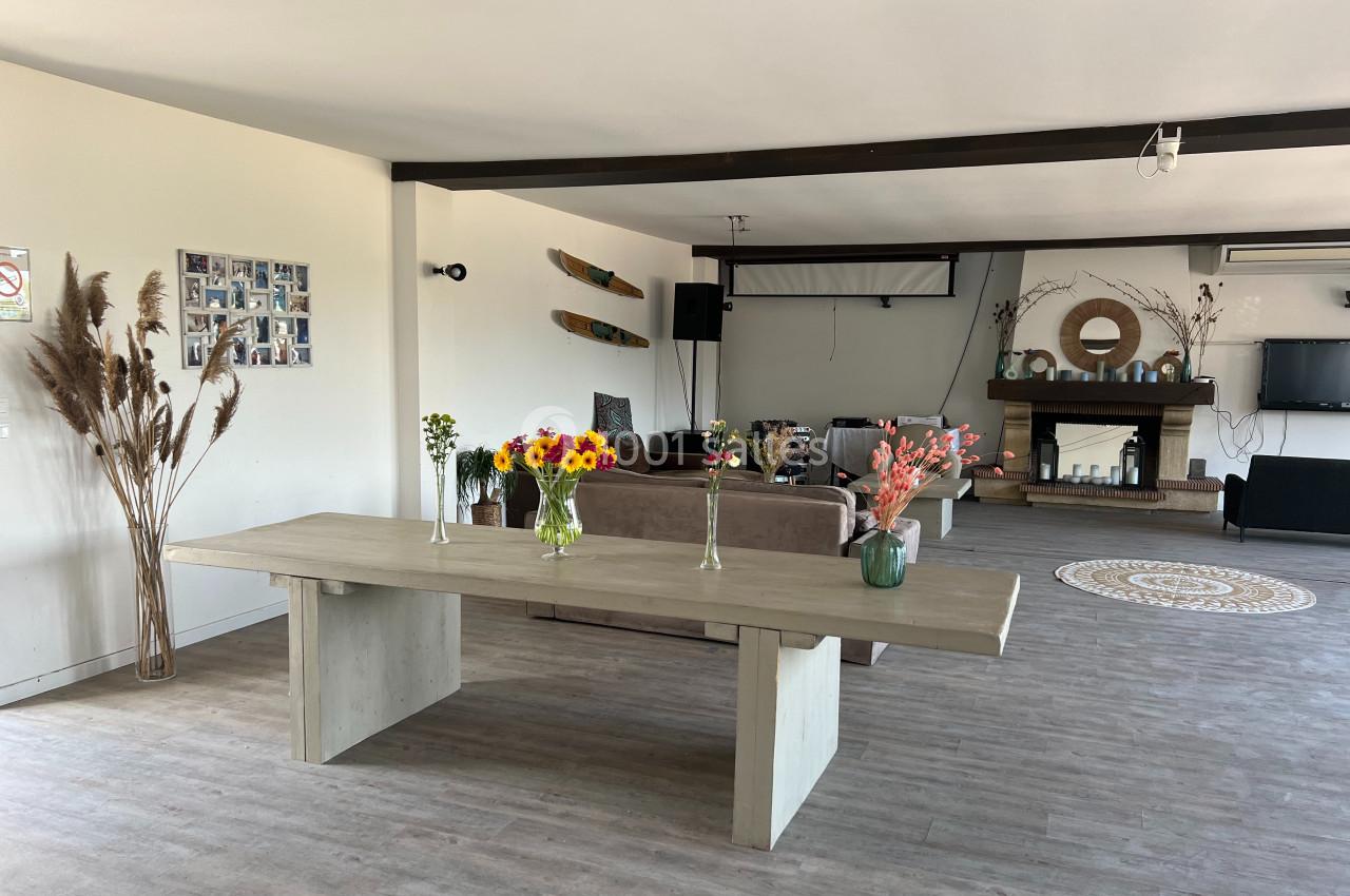 Salle lumineuse avec table en bois décorée de fleurs, canapés, cheminée, et éléments de décoration murale.