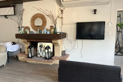 Vue d'une rivière bordée de végétation avec une maison au toit rouge et un ciel partiellement nuageux au coucher du soleil.