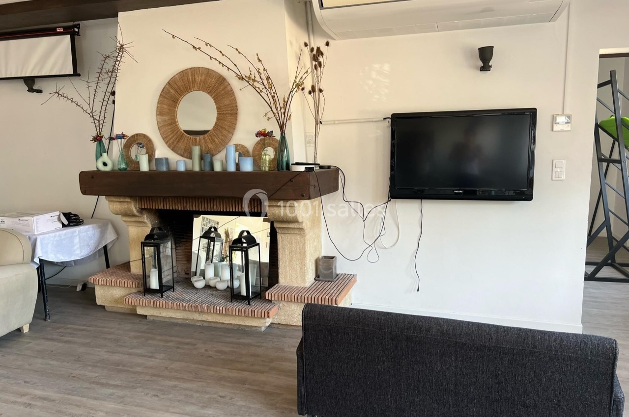 Cheminée décorative avec bougies et miroirs, téléviseur mural et climatisation dans un salon au sol en parquet.