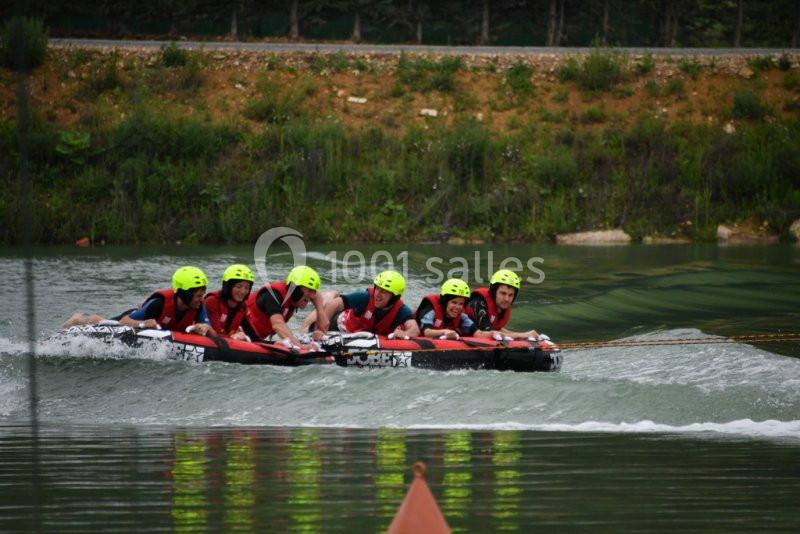 Des personnes portant des casques et des gilets de sauvetage font du bouée tractée sur un plan d'eau calme.