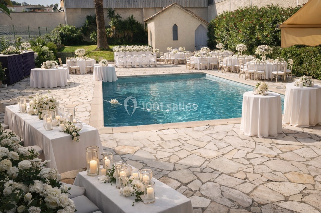 Aménagement extérieur pour un mariage avec tables décorées de fleurs blanches autour d'une piscine.
