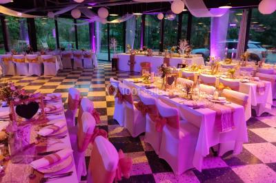 Miniature Location salle Fampoux (Pas-de-Calais) - L'hermitage de Fampoux #2 Salle sombre avec éclairage violet, plafond métallique, tables et chaises dispersées sur un sol à carreaux.