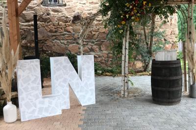 Miniature Location salle Chambost-Allières (Rhône) - Domaine de Montfriol #19 Structure en bois avec décorations de mariage, incluant des lettres blanches, un tonneau et des fleurs suspendues.