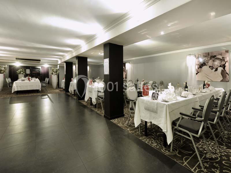 Salle de réception élégante avec tables dressées, nappes blanches et éclairage tamisé.