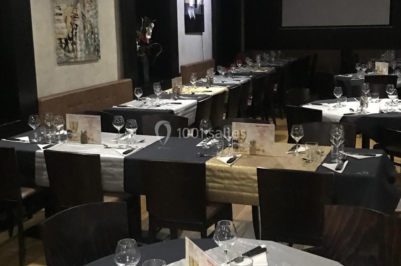 Salle de restaurant avec tables dressées, nappes colorées, verres et menus disposés pour un service.