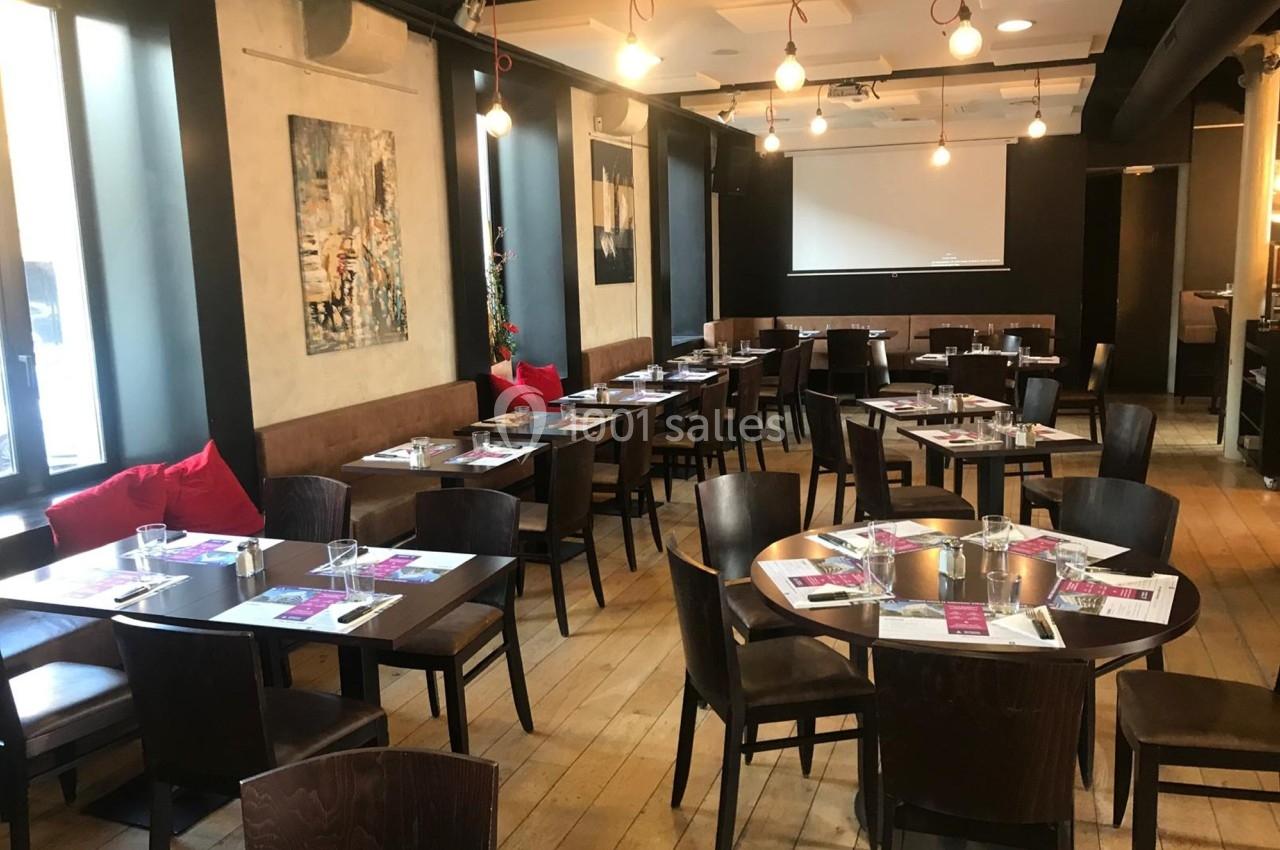 Salle de restaurant lumineuse avec tables en bois, chaises assorties, et décorations murales modernes.