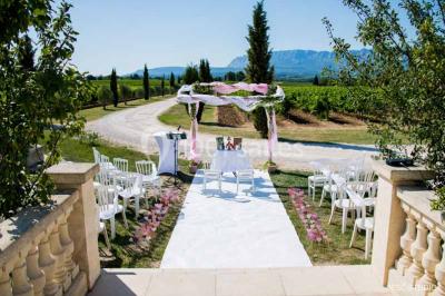 Allée bordée de cyprès et de vignes avec une vue sur une montagne en arrière-plan, sous un ciel clair.