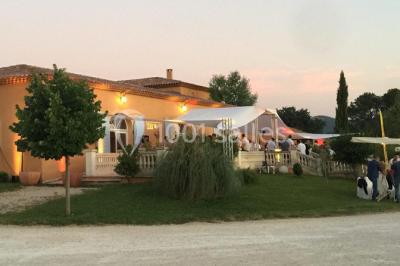Allée bordée de cyprès et de vignes avec une vue sur une montagne en arrière-plan, sous un ciel clair.