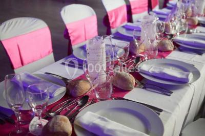 Table de pique-nique en bois sur un sol de gravier, entourée d'arbres dans un cadre naturel.