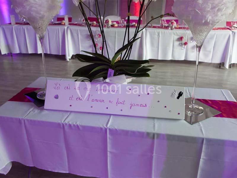 Panneau décoratif avec une citation romantique, posé sur une table ornée de nappes et de décorations de mariage.