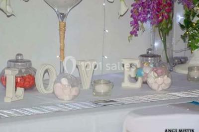 Table de pique-nique en bois sur un sol de gravier, entourée d'arbres dans un cadre naturel.