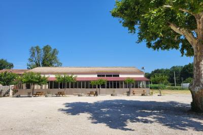 Table de pique-nique en bois sur un sol de gravier, entourée d'arbres dans un cadre naturel.