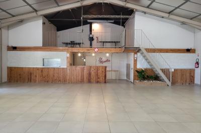 Table de pique-nique en bois sur un sol de gravier, entourée d'arbres dans un cadre naturel.