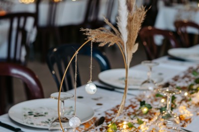 Table de pique-nique en bois sur un sol de gravier, entourée d'arbres dans un cadre naturel.