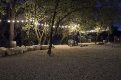 Table de pique-nique en bois sur un sol de gravier, entourée d'arbres dans un cadre naturel.