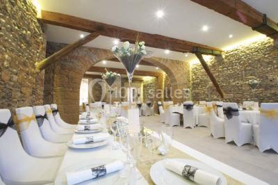 Tente blanche avec mobilier de jardin noir sur tapis rouge, installée devant une entrée vitrée d'un bâtiment beige.