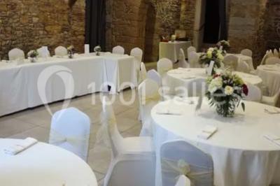 Tente blanche avec mobilier de jardin noir sur tapis rouge, installée devant une entrée vitrée d'un bâtiment beige.