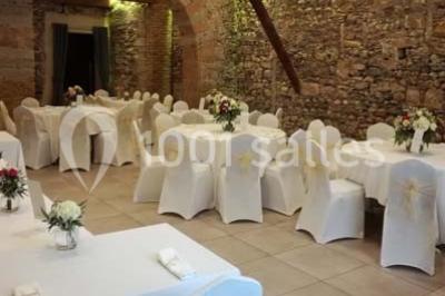 Tente blanche avec mobilier de jardin noir sur tapis rouge, installée devant une entrée vitrée d'un bâtiment beige.