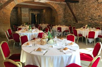 Tente blanche avec mobilier de jardin noir sur tapis rouge, installée devant une entrée vitrée d'un bâtiment beige.