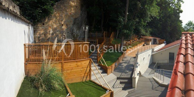 Location salle Lyon 9 (Rhône) - Hub de l'Ile Barbe #23 Terrasses en bois avec escaliers et espaces verts, adossées à une paroi rocheuse et entourées de végétation.