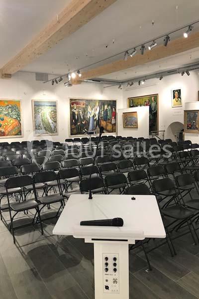 Location salle Lyon 9 (Rhône) - Hub de l'Ile Barbe #4 Salle de conférence avec des rangées de chaises noires vides, un pupitre et un micro au premier plan.