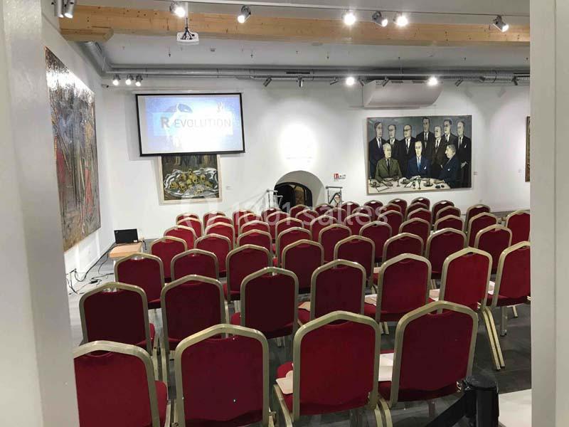 Location salle Lyon 9 (Rhône) - Hub de l'Ile Barbe #3 Salle de conférence avec des rangées de chaises rouges, un écran de projection et des tableaux accrochés aux murs.