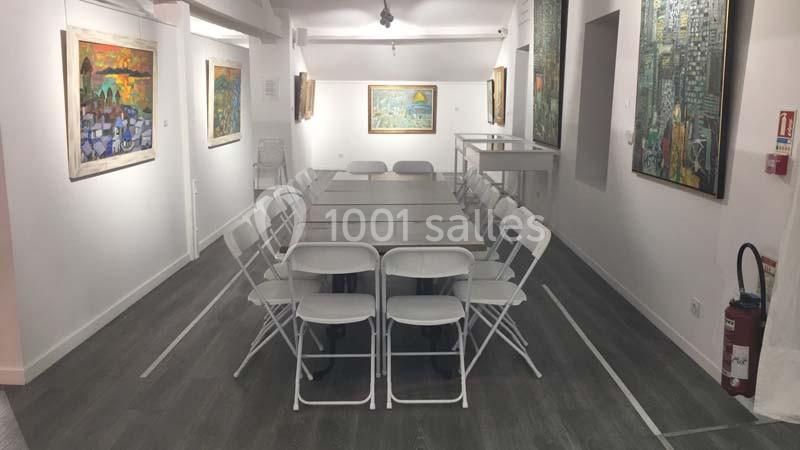 Location salle Lyon 9 (Rhône) - Hub de l'Ile Barbe #5 Salle d'exposition lumineuse avec une grande table entourée de chaises pliantes, entourée de peintures accrochées aux murs.