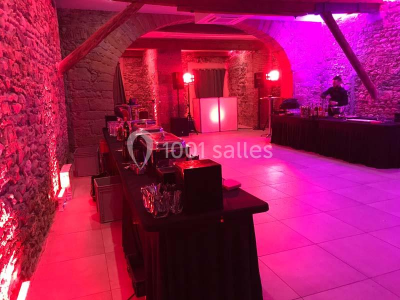 Location salle Lyon 9 (Rhône) - Hub de l'Ile Barbe #21 Salle en pierre éclairée par des lumières rouges et violettes, avec buffets installés et un bar en arrière-plan.