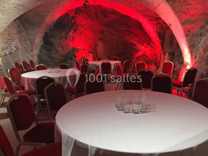 Location salle Lyon 9 (Rhône) - Hub de l'Ile Barbe #14 Salle voûtée en pierre éclairée de rouge, aménagée avec des tables rondes dressées de nappes blanches et des chaises rouges.