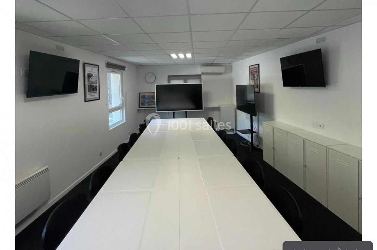 Location salle Lyon 9 (Rhône) - Hub de l'Ile Barbe #24 Salle de réunion lumineuse avec une grande table blanche, des chaises noires, plusieurs écrans et des affiches aux murs.