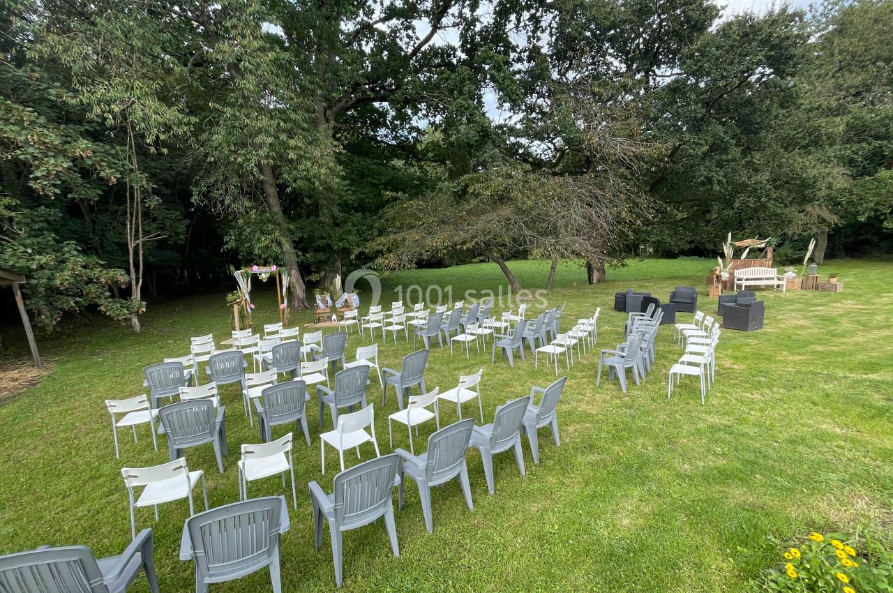 Chaises disposées en rangées sur une pelouse, face à une arche décorée pour une cérémonie en extérieur.