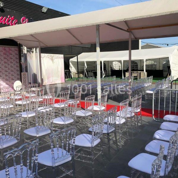 Chaises transparentes alignées sous des tentes blanches, disposées face à une scène avec tapis rouge en extérieur.