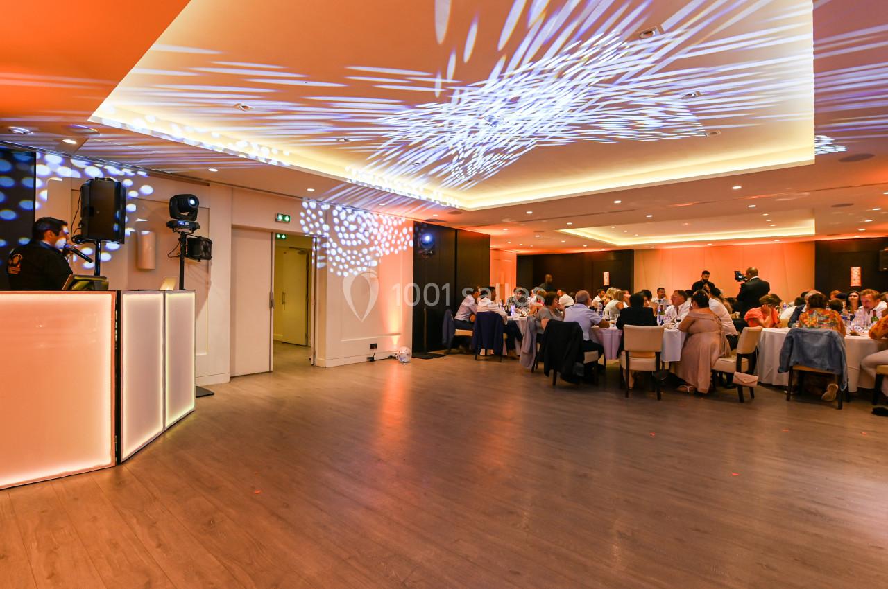 Salle de réception avec invités assis à des tables, éclairage tamisé et projections lumineuses au plafond.