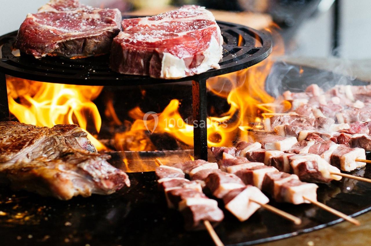 Viande grillée sur un barbecue avec flammes, comprenant steaks et brochettes en cours de cuisson.