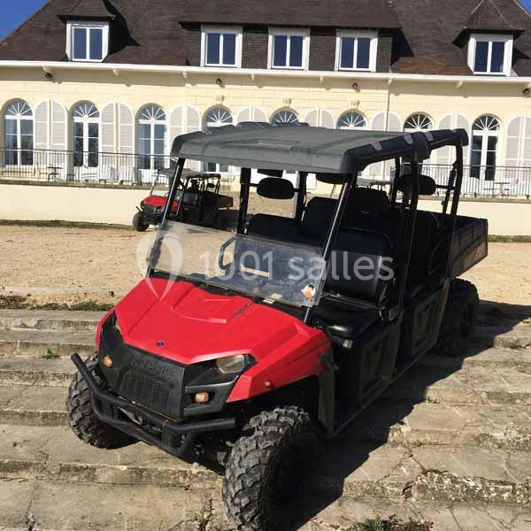 Véhicule tout-terrain rouge stationné sur des marches en pierre devant un bâtiment avec de grandes fenêtres.
