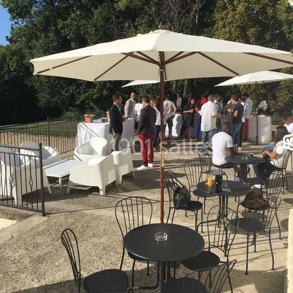 Terrasse ensoleillée avec tables, chaises et parasols, où des personnes discutent et se détendent.