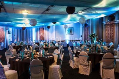 Salle de restaurant lumineuse avec des tables en bois, chaises bleues et grandes fenêtres laissant entrer la lumière…