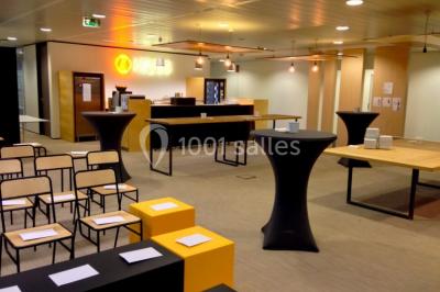 Façade vitrée d'un bâtiment moderne avec une terrasse en bois éclairée par le soleil.