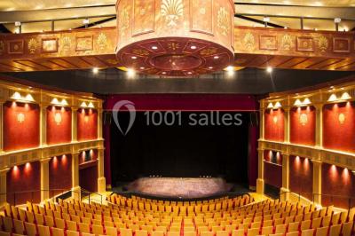 Salle spacieuse avec parquet en bois clair, colonnes blanches, plafonds ondulés et luminaires suspendus.